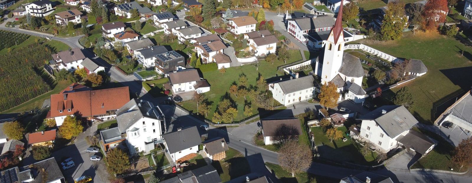 Luftansicht der Gemeinde Gaimberg im Herbst mit der Pfarrkirche im Zentrum des Bildes