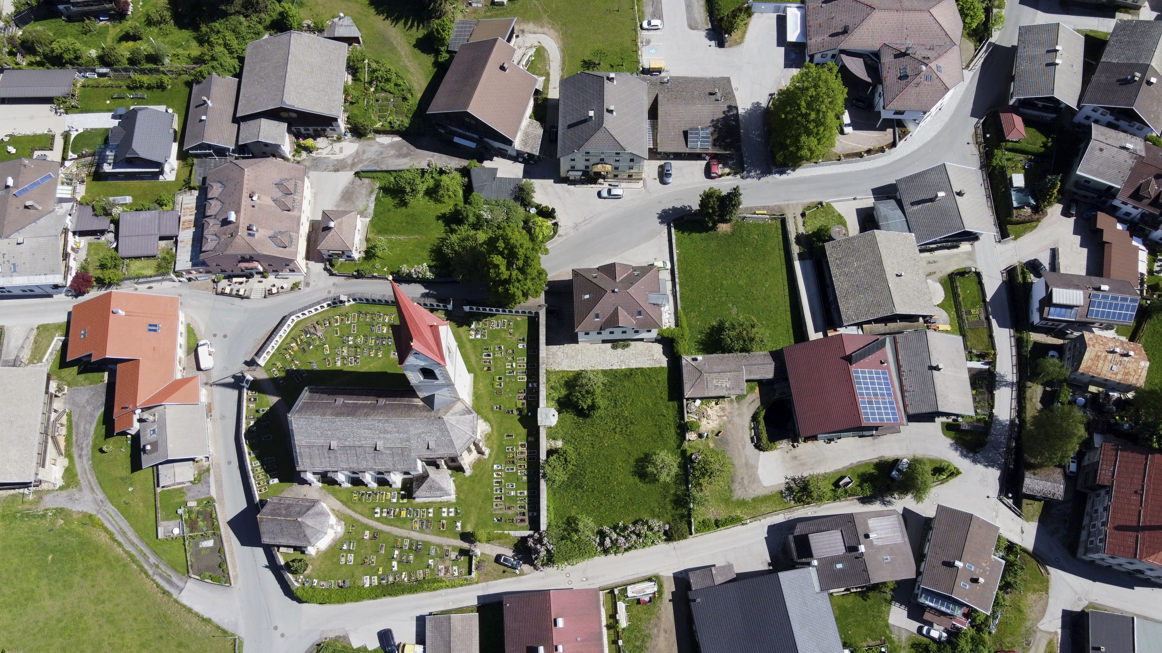 Der Dorfkern von Oberlienz aus der Vogelperspektive mit Kirche, Friedhof, Straßen und Häuser im Ortskern.