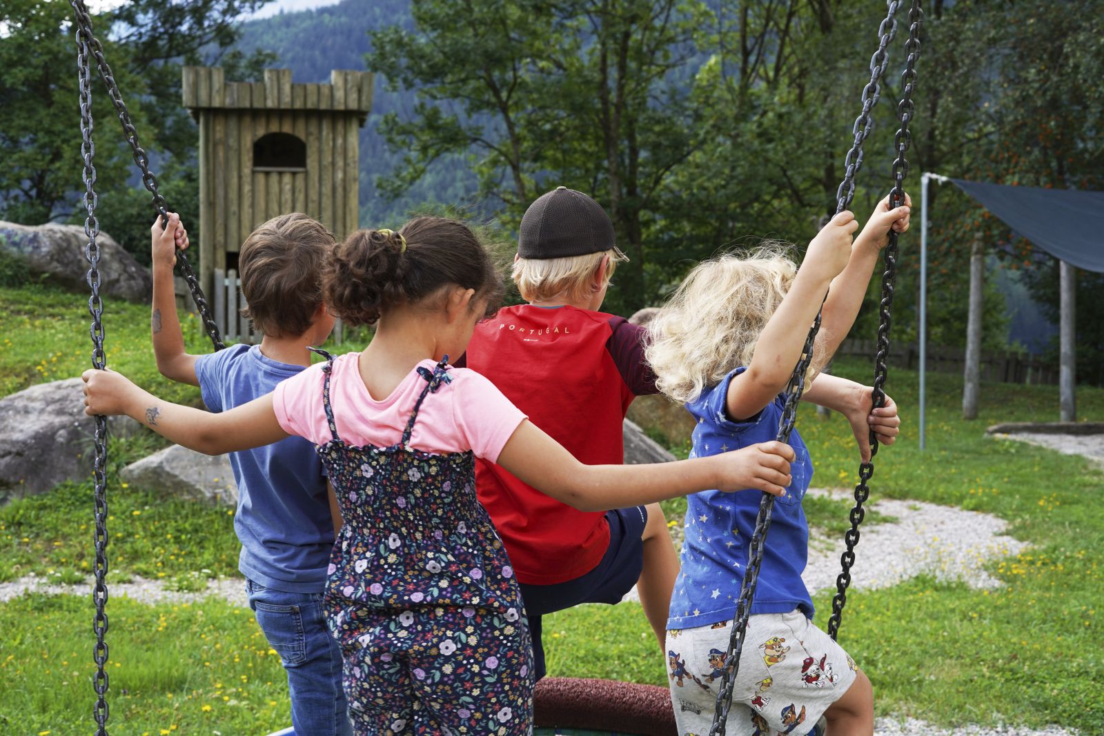 vier Kinder auf einer Schaukel am Spielplatz