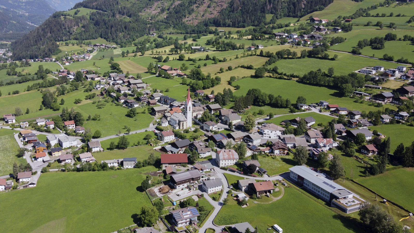 Luftaufnahme der Gemeinde Oberlienz mit der Kirche im Zentrum des Bildes