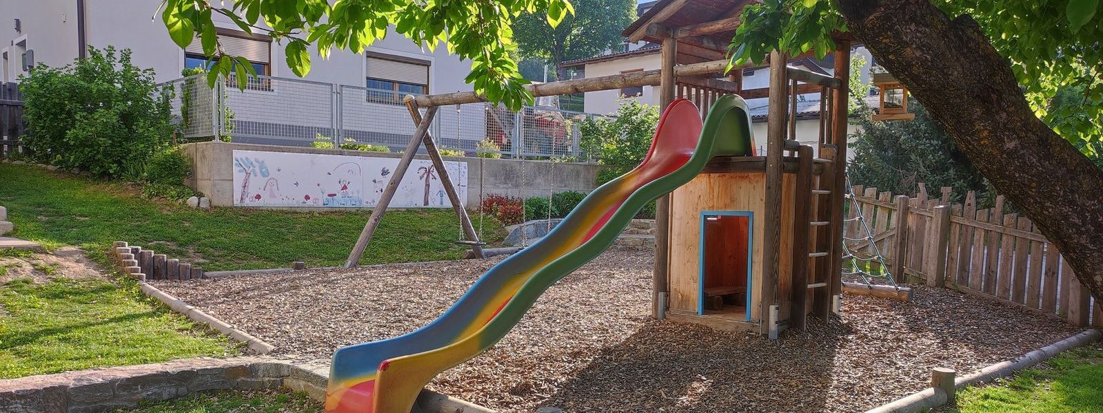 Bunte Rutsche auf Holzhaus und einer Schaukel am Spielplatz