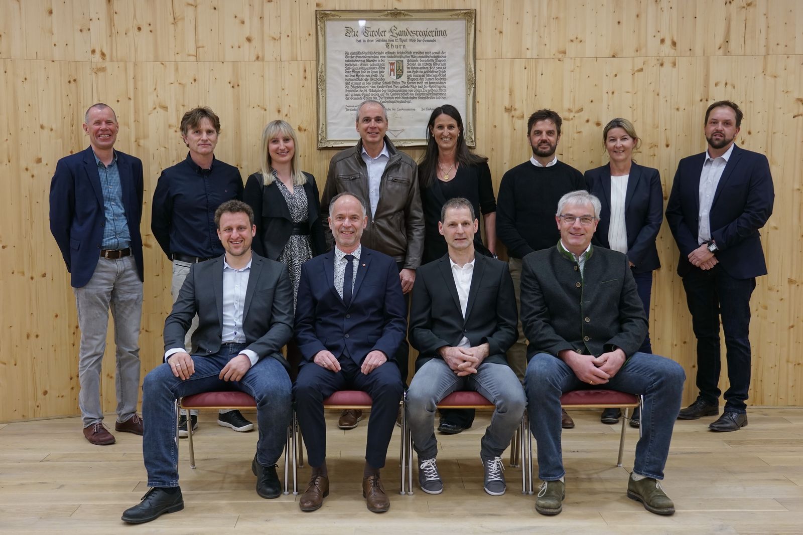 Der Gemeinderat von Thurn. 4 Personen sitzen. 8 Personen stehen dahinter