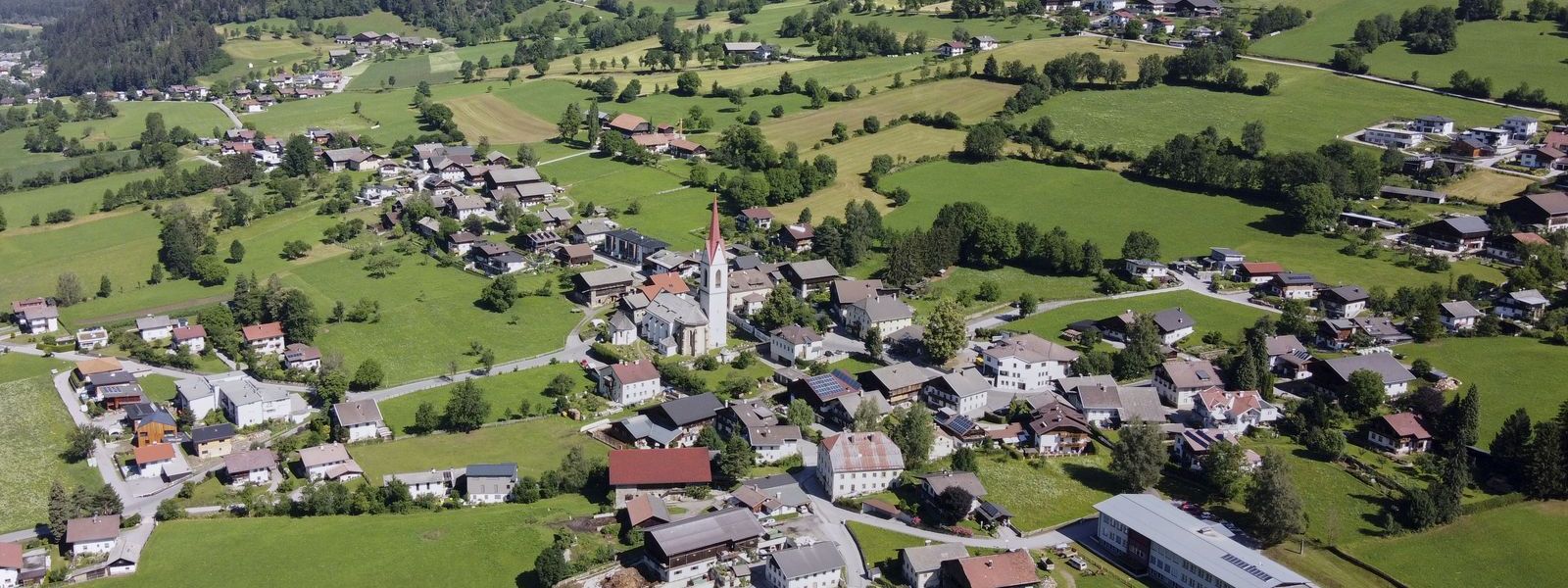 Luftaufnahme im Herbert der Gemeinde Oberlienz mit der Kirche im Zentrum.