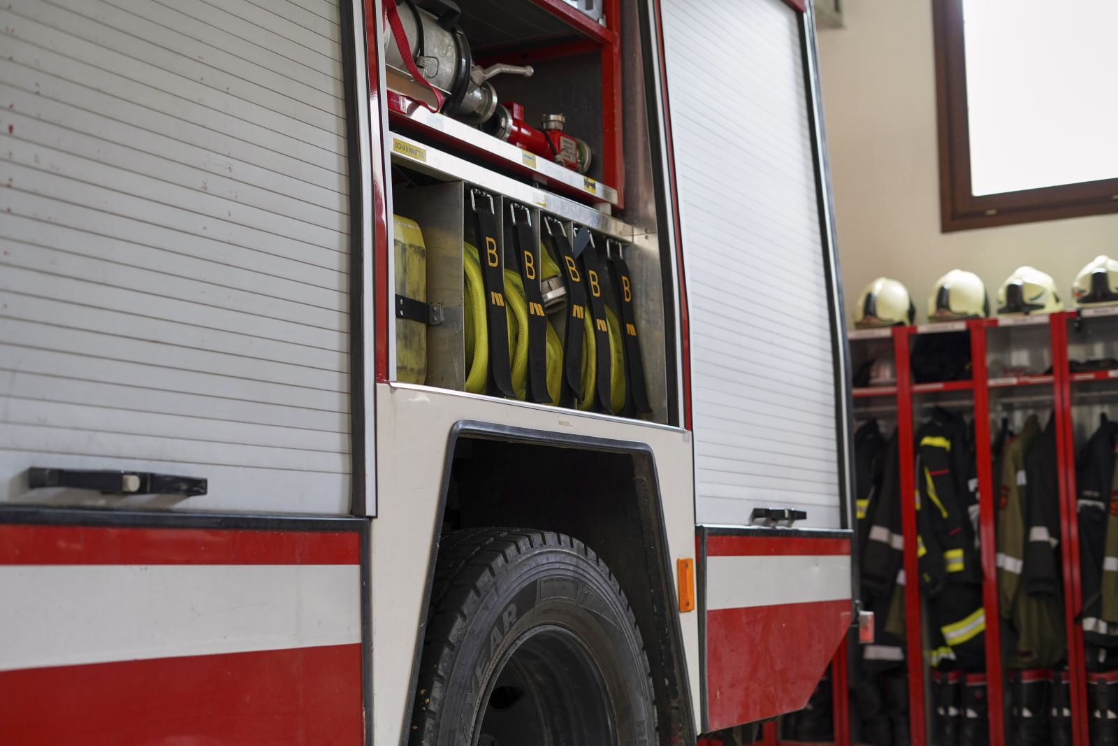 Material in Feuerwehrauto im Hintergrund Spinte mit Einsatzjacken und Helmen