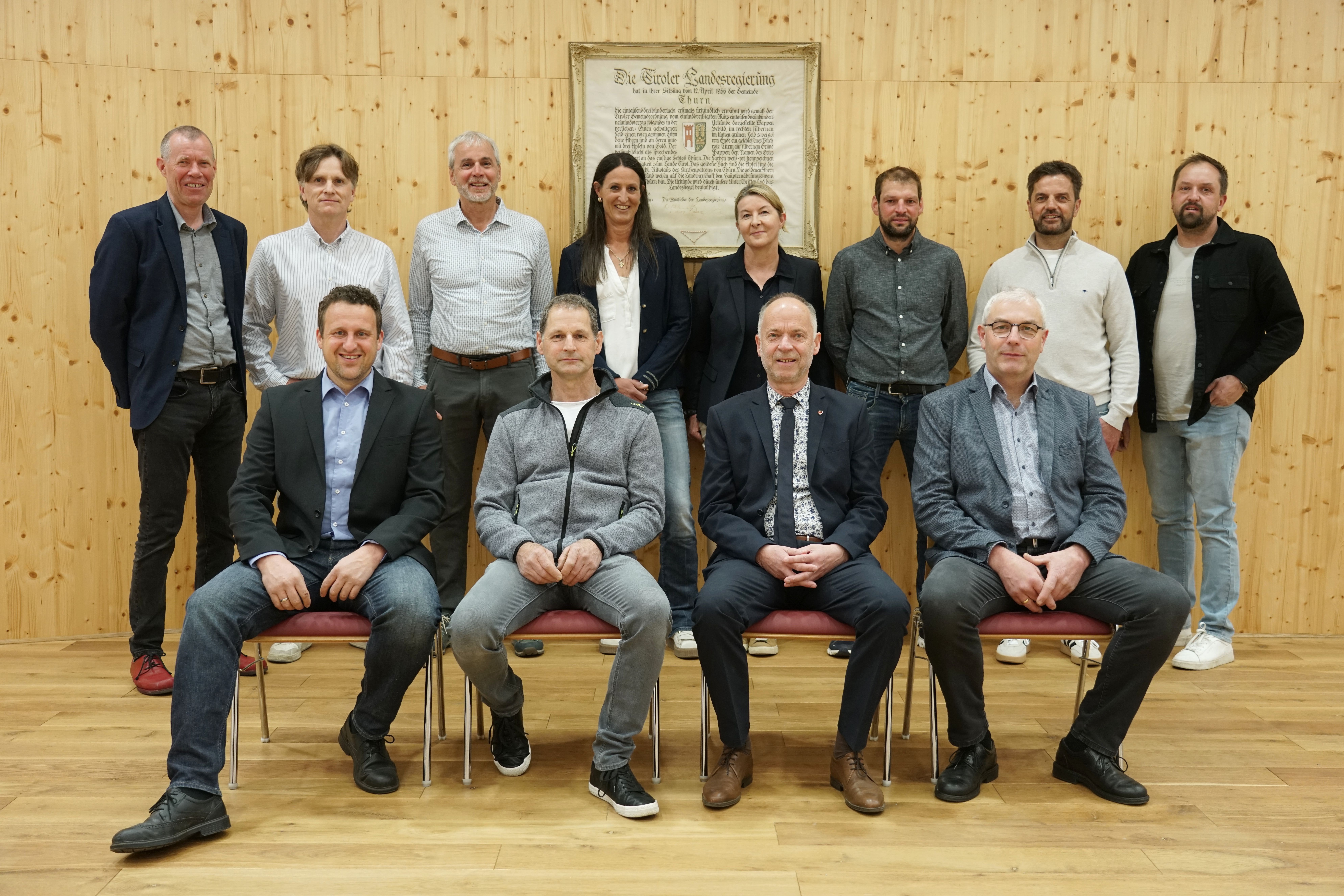 Der Gemeinderat von Thurn. 4 Personen sitzen. 8 Personen stehen dahinter